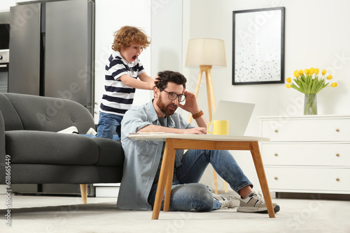 Fotografie Little boy bothering his father at home