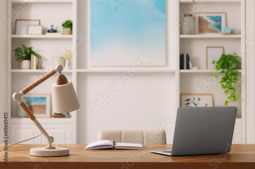 Interior design. Cosy workplace with laptop and lamp on wooden table near abstract picture between shelves © New Africa