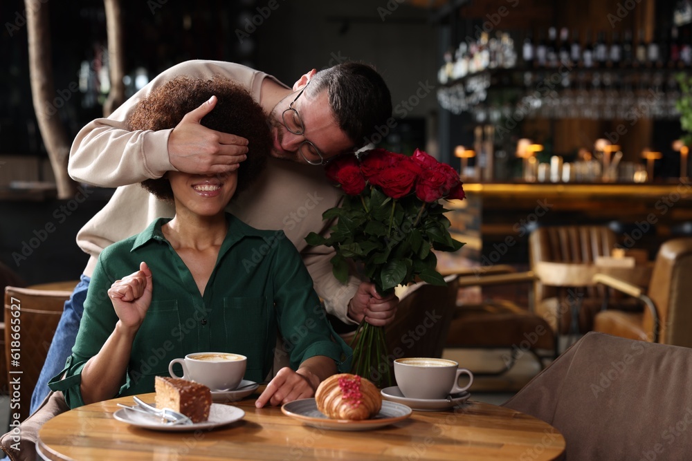 International dating. Handsome man presenting roses to his girlfriend in restaurant, space for text International dating. Handsome man presenting roses to his girlfriend in restaurant, space for text