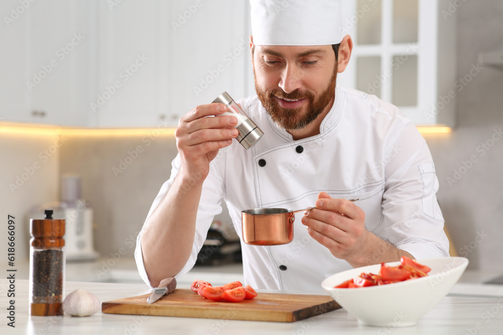 Professional chef adding salt into scoop at marble table in kitchen Professional chef adding salt into scoop at marble table in kitchen