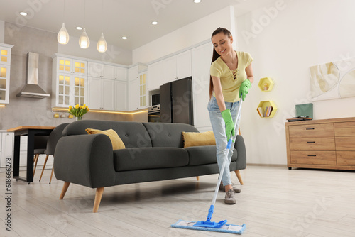 Spring cleaning. Young woman with mop washing floor at home photo