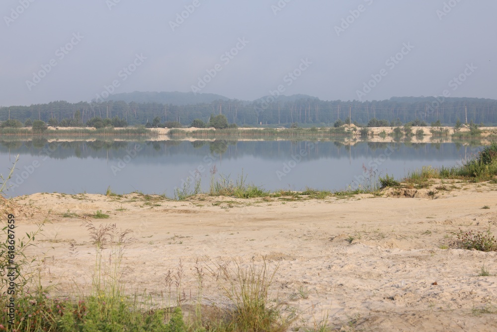 Picturesque view of lake and sandy beach on summer day