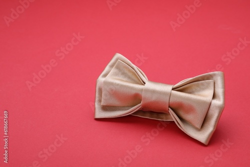 Stylish beige bow tie on red background, space for text