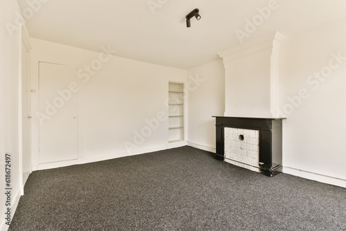an empty room with white walls and black carpet, there is a wood burning stove in the wall to the right