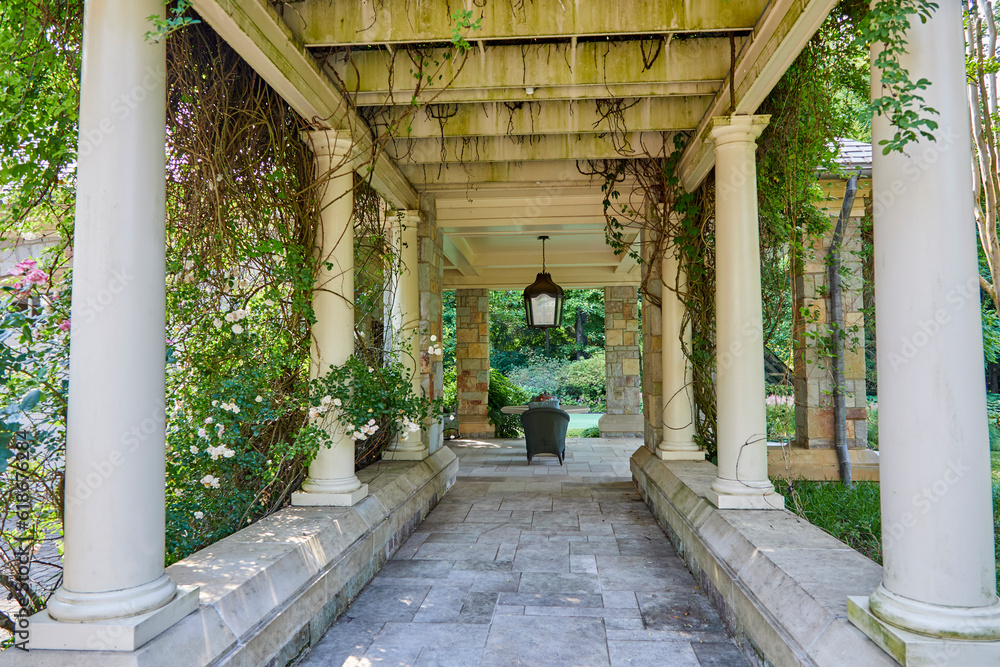 Outdoor covered porch with columns and greenery growing up the sides