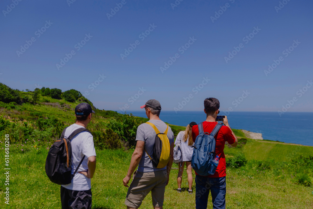 Group of tourists taking pictures of scenery on seashore using their phones Group of tourists taking pictures of scenery on seashore using their phones