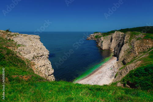 White rocks with green grass by sea on summer sunny day