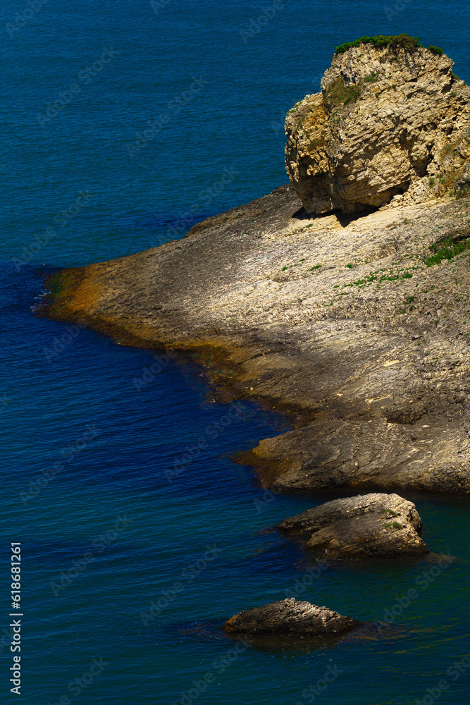 Green rocky island in sea closeup on summer sunny day.