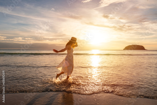 Photography Young woman traveler dancing and enjoying beautiful Sunset on the tranquil beach