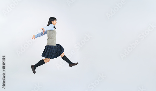 ジャンプする制服の女子学生 © metamorworks