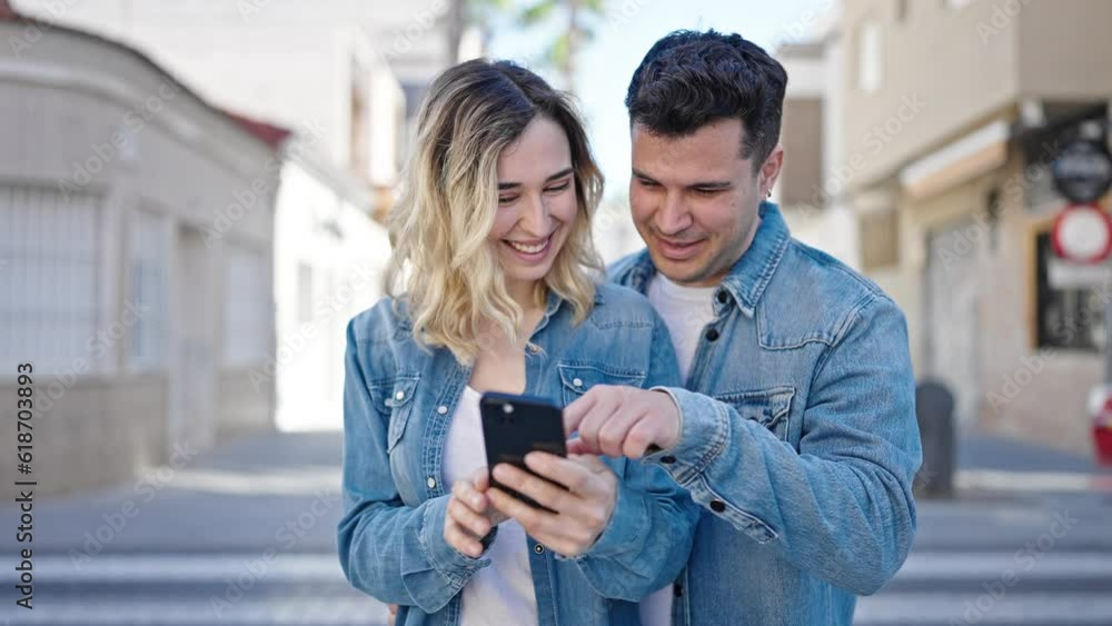 Man and woman couple standing together using smartphone at street Man and woman couple standing together using smartphone at street