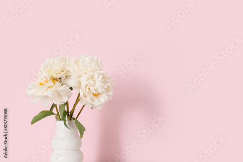 Vase of white peonies on pink background