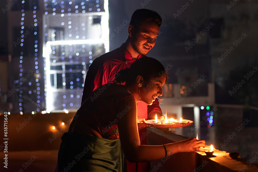 Indian couple placing diya with smiling at home on Diwali Indian couple placing diya with smiling at home on Diwali