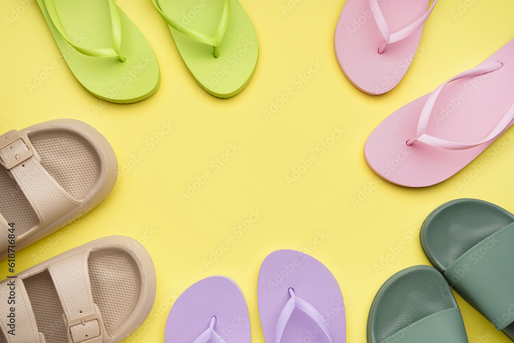 Frame made of different color flip-flops on yellow background Frame made of different color flip-flops on yellow background
