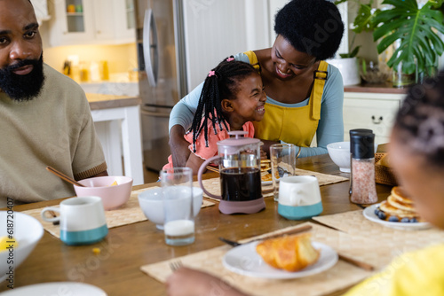 African american mother and father having breakfast with cheerful daughter at dining table