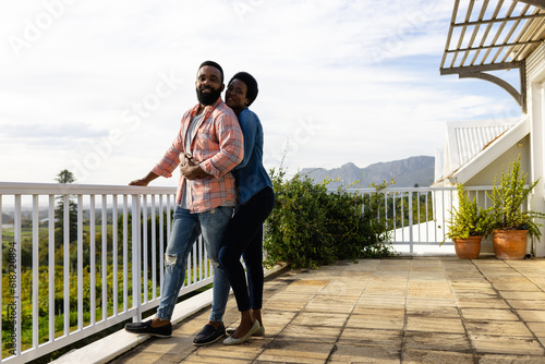 Happy african american couple embracing and staying on sunny terrace