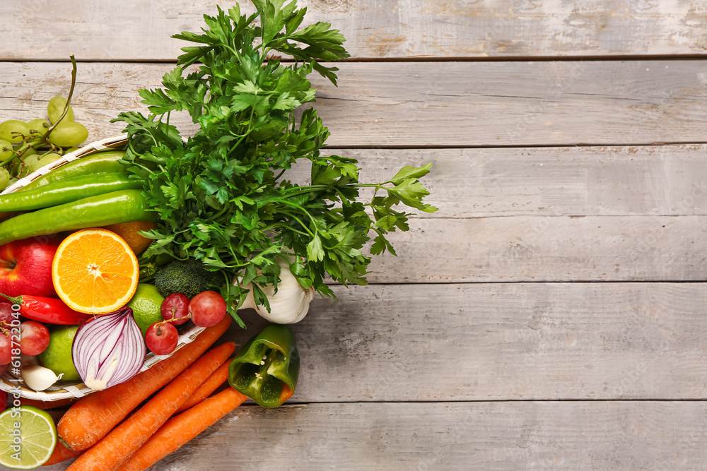 Wicker bowl with different fresh fruits and vegetables on grey wooden background Wicker bowl with different fresh fruits and vegetables on grey wooden background
