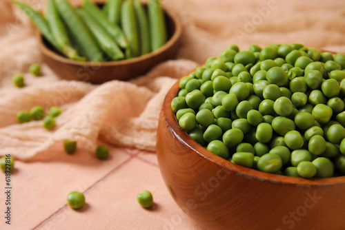 Bowls with fresh green peas on pink tile table
