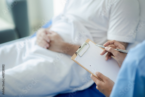 Patient on an inpatient hospital bed with a doctor examining and asking for information about the symptoms in order to diagnose the correct and appropriate treatment. The concept of medical treatment.