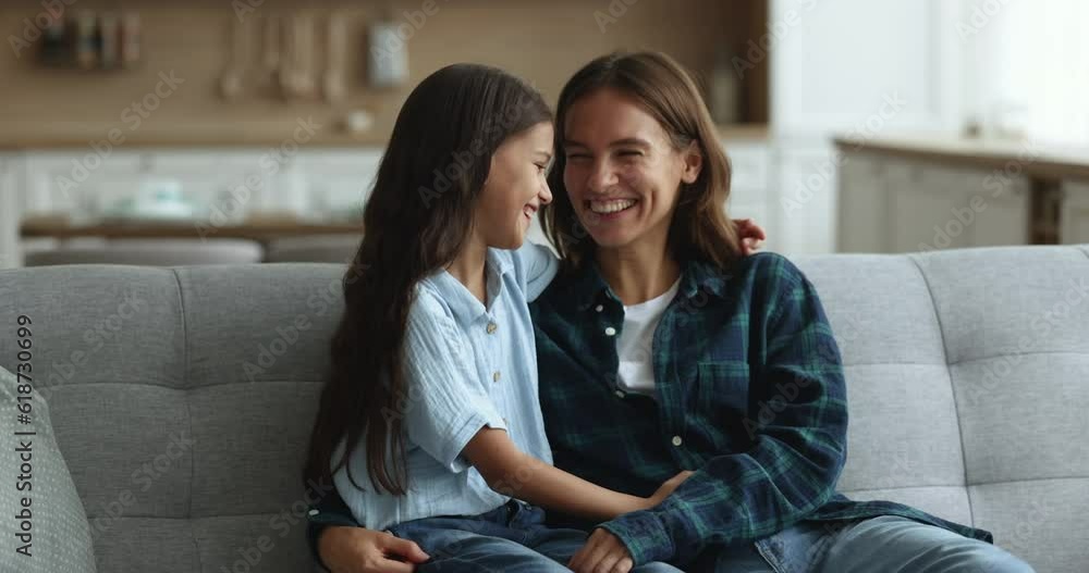 Happy loving mother hugging with affection little 10s daughter sit together on cozy sofa, discuss news, enjoy leisure time and good close relationship. Happy motherhood, communication, family ties Happy loving mother hugging with affection little 10s daughter sit together on cozy sofa, discuss news, enjoy leisure time and good close relationship. Happy motherhood, communication, family ties