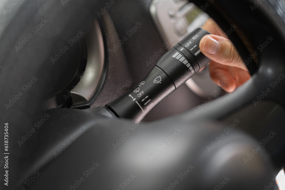 Naklejka premium Woman hand use turn signal switch, close-up. Turning car lights