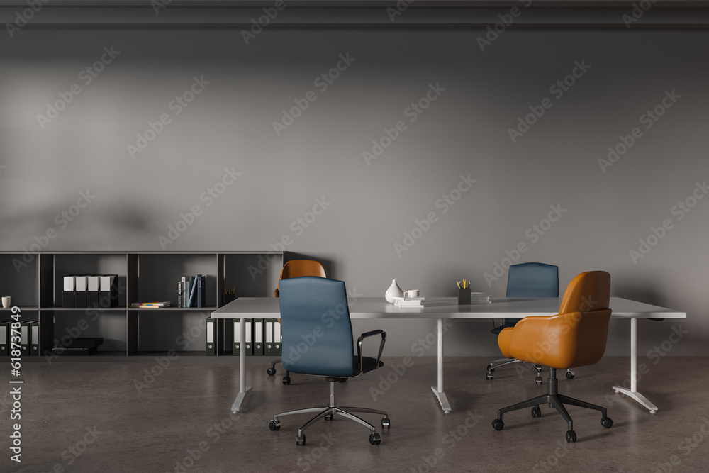 Grey coworking interior with a table and chairs, shelf and mockup wall