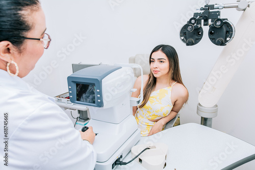 Woman patient having consultation with optometrist in office. Optometrist with female patient in the autorefractor photo