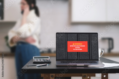 a laptop computer standing on a table with a system hacking message on the screen.