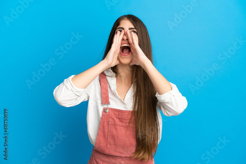 Young caucasian woman isolated on blue background shouting and announcing something