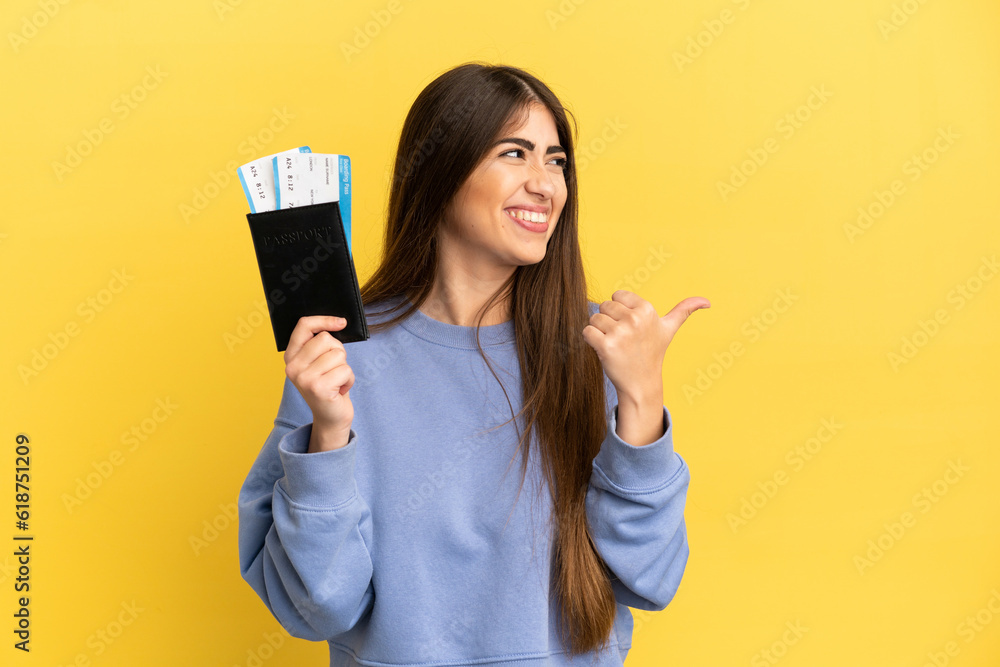 Young caucasian woman holding a passport isolated on yellow background pointing to the side to present a product Young caucasian woman holding a passport isolated on yellow background pointing to the side to present a product