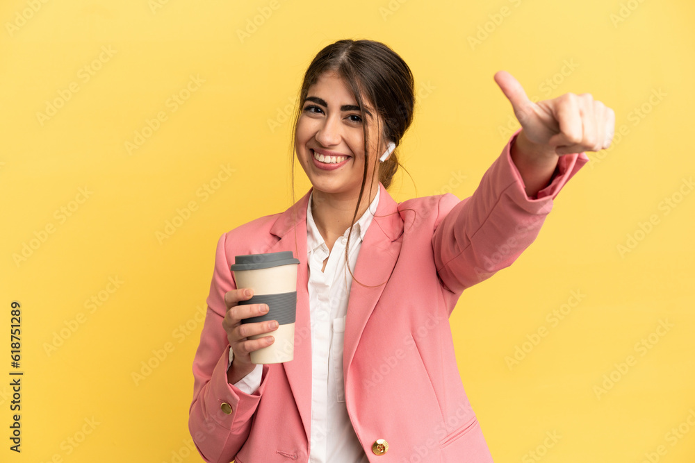 Business caucasian woman isolated on yellow background giving a thumbs up gesture Business caucasian woman isolated on yellow background giving a thumbs up gesture