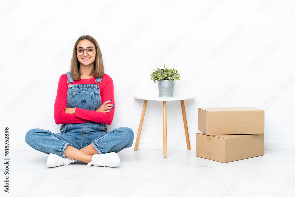 Young caucasian woman sitting on the floor among boxes keeping the arms crossed in frontal position