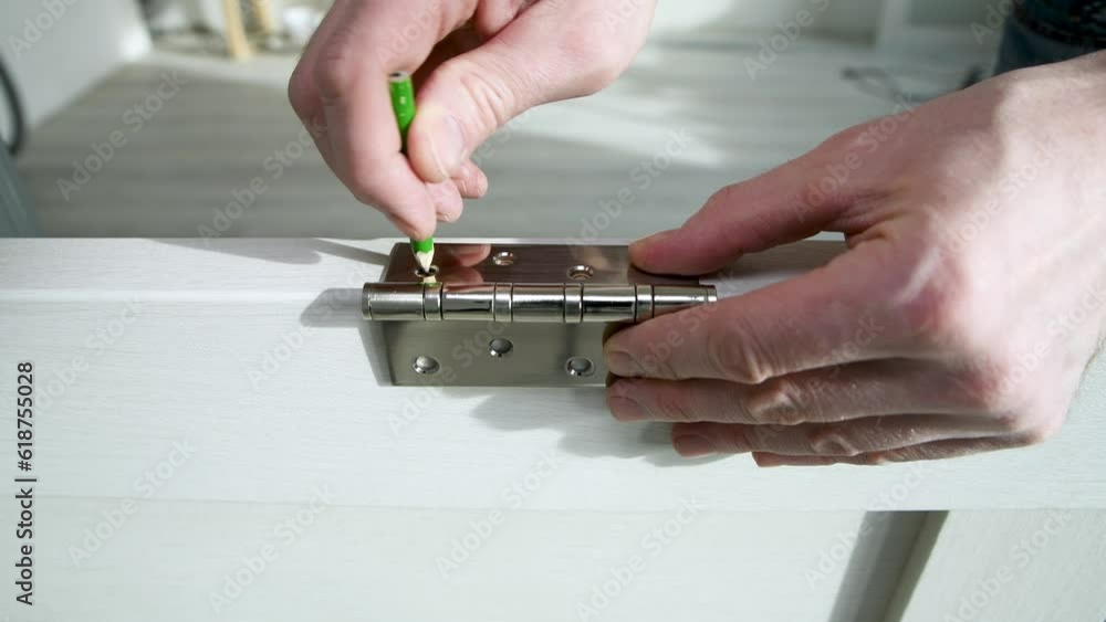 Worker marks with a pencil the places for the screws of the door hinge. Repair and decoration of apartments. Carpentry work. Door installation. Worker marks with a pencil the places for the screws of the door hinge. Repair and decoration of apartments. Carpentry work. Door installation.