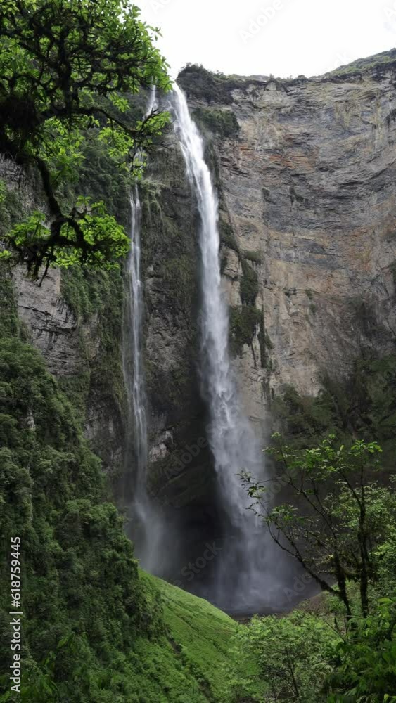 Slow motion of a big foamy waterfall coming down the huge cliff in the forest Slow motion of a big foamy waterfall coming down the huge cliff in the forest