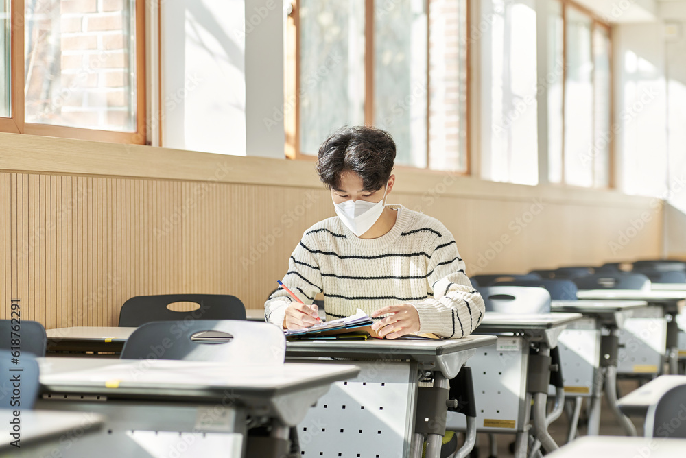 A young university student model wearing a mask while studying in a university classroom in South Korea, Asia during the pandemic. A young university student model wearing a mask while studying in a university classroom in South Korea, Asia during the pandemic.