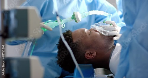 Diverse surgeons giving anesthesia to patient in operating theatre, slow motion photo