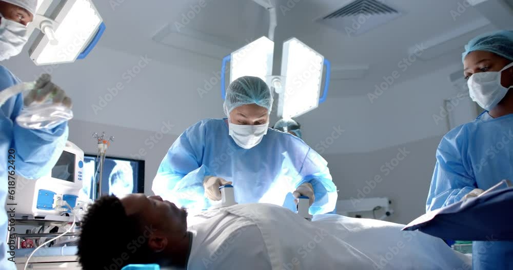 Diverse surgeons using defibrillator on patient in operating theatre, slow motion Diverse surgeons using defibrillator on patient in operating theatre, slow motion