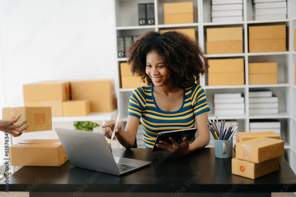 Small business entrepreneur SME freelance African woman working at home office, BOX,tablet and laptop online, marketing, packaging, delivery, e-commerce concept Small business entrepreneur SME freelance African woman working at home office, BOX,tablet and laptop online, marketing, packaging, delivery, e-commerce concept