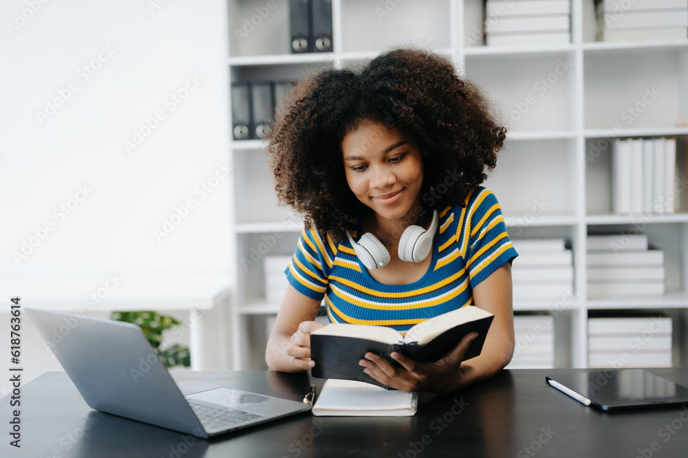 Female students note from the books at the African girl library sitting at the desk using laptop computer and tablet to search an online informations. Female students note from the books at the African girl library sitting at the desk using laptop computer and tablet to search an online informations.