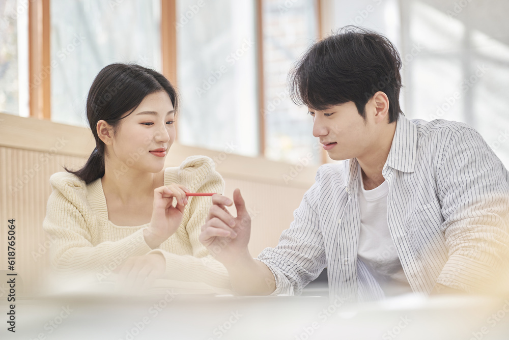 Colleague, friend, motivator, young male model comforting a distressed young female college student model sitting at a desk in a university classroom in Asia Korea. Colleague, friend, motivator, young male model comforting a distressed young female college student model sitting at a desk in a university classroom in Asia Korea.