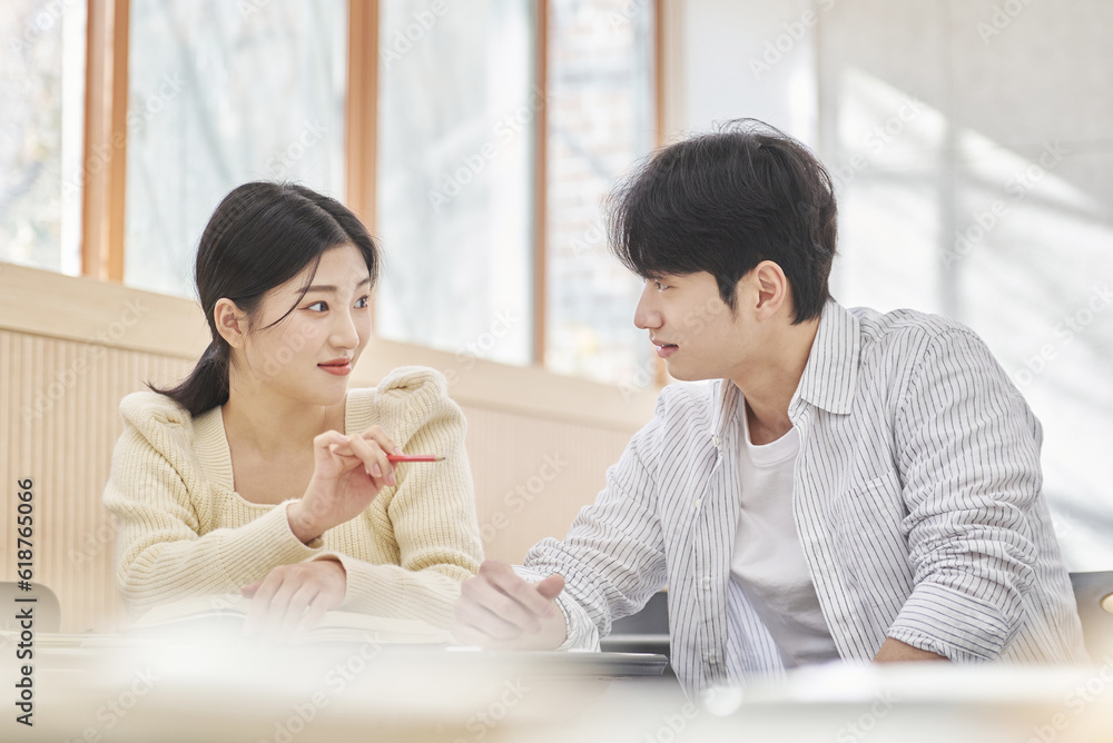 Colleague, friend, motivator, young male model comforting a distressed young female college student model sitting at a desk in a university classroom in Asia Korea. Colleague, friend, motivator, young male model comforting a distressed young female college student model sitting at a desk in a university classroom in Asia Korea.
