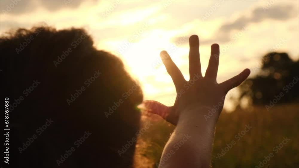 Silhouette of little girl raising hand over sunset sky, enjoying life and nature. Child on summer field enjoying sunlight. Preteen kid in warm sunlight rays. Air, environment concept. Dream of flying Silhouette of little girl raising hand over sunset sky, enjoying life and nature. Child on summer field enjoying sunlight. Preteen kid in warm sunlight rays. Air, environment concept. Dream of flying