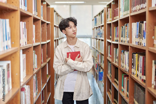 Young variously facial expression male college student model looking for and reading a book on a shelf in a university library in Asia South Korea