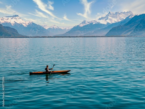 Person in a canoe navigating a tranquil mountain lake, taking in the majestic views