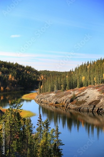 Fotografiet Scenic landscape of a river flowing along a hillside covered with a lush green f