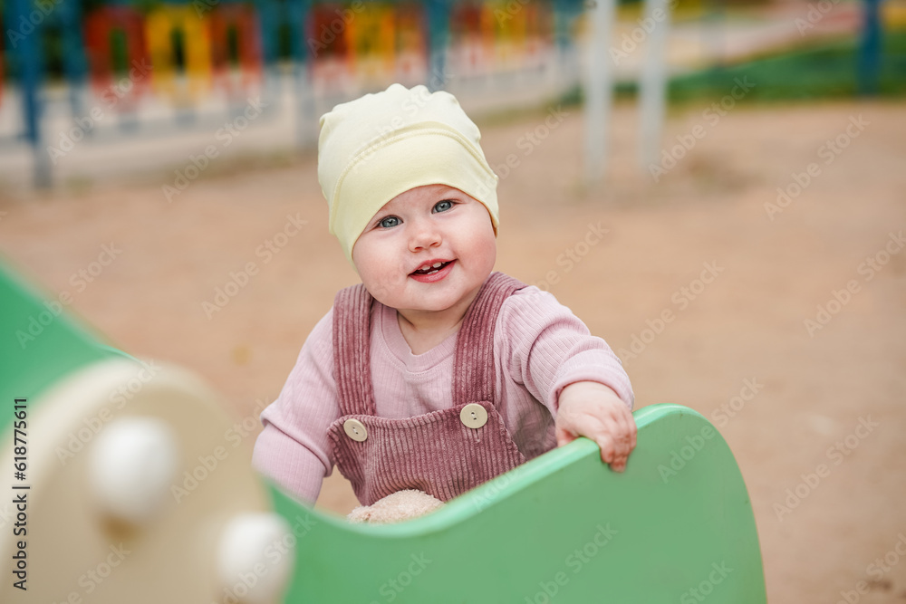 Cheerful baby toddler plays on the playground in the summer Cheerful baby toddler plays on the playground in the summer