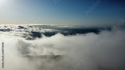 Stunning view of the clouds over the mountains covered in dense trees at sunlight