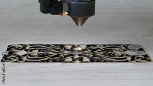 Traditional motifs engraved on wood with CNC laser machine. Image of computer-controlled cnc laser machine for engraving motifs on wood.