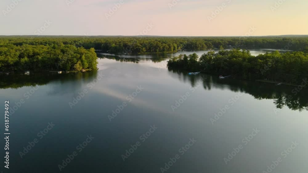 Drone view over a lake surrounded by green vegetation during golden hour Drone view over a lake surrounded by green vegetation during golden hour