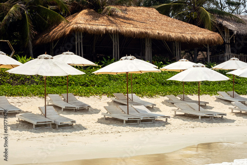 Empty sun loungers on the beach. Beach chairs and umbrellas. Vacation on tropical beach